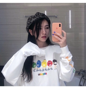 Close-up of white crew neck sweatshirt featuring colorful cartoon m&m's graphic print