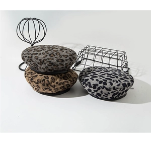 Detail view of leopard print wool berets in grey and brown with black leather trim