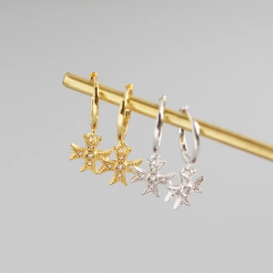 Detail of gold and silver S925 sterling silver hoop earrings with star pendants and diamonds