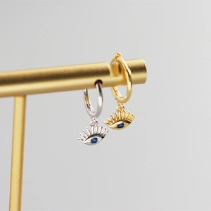 Detail of 925 sterling silver eye earrings with blue zircon on a jewelry stand