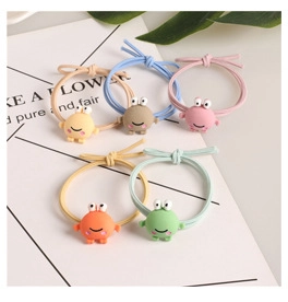 Detailed view of colorful elastic hair ties with cute cartoon monster charms in 5 colors