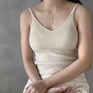 Detailed view of 925 silver heart key pendant on a gold chain against a beige knit top