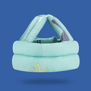 Close-up of mint green baby safety helmet with thick padding and cartoon fabric texture