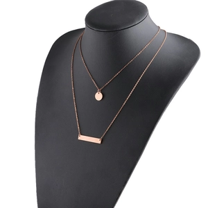 Detail of rose gold double layer necklace with bar and disc pendants on black bust