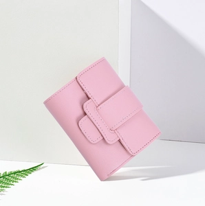 Close-up of pink faux leather trifold wallet with buckle closure and minimalist design