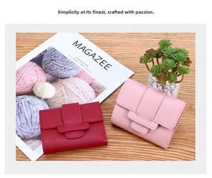 Detail view of pink and dark red minimalist leather wallets on a wooden tabletop