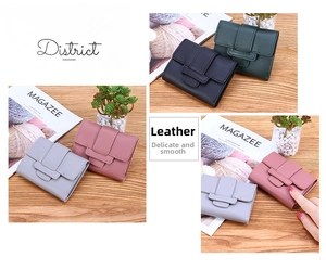 Multiple colors of women's short leather wallets displayed on a wooden desk setup