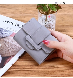 Close-up of a compact gray trifold wallet with litchi grain texture held in hand