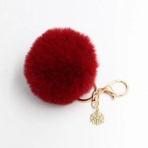 Detail eines roten flauschigen Bommel-Schlüsselanhängers mit goldenem Schneeflocken-Anhänger