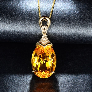 Detailed view of an oval yellow gemstone pendant with tiny crystals on a gold chain