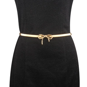 Close-up of a delicate gold bow buckle on a slim elastic belt for dresses