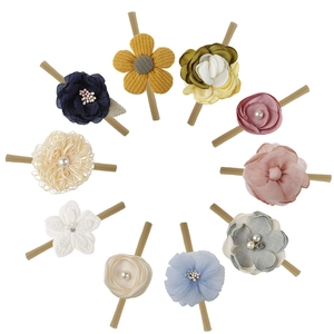 Flat lay of 10 colorful fabric flower nylon headbands for baby girls with pearl details