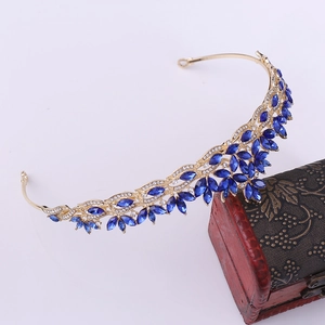 Detailed close-up of golden bridal crown with blue crystals on a vintage red jewelry box