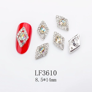 Detail of diamond-shaped nail charms with colorful AB rhinestones on a red nail