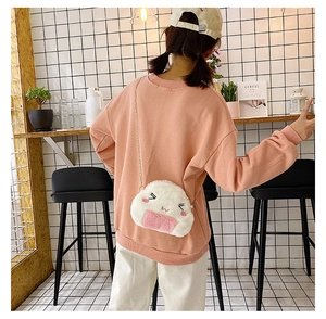 Detail of cute white plush rice ball crossbody bag with chain strap on model in cafe