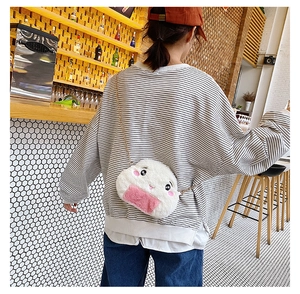 Detail of cute rice ball plush crossbody bag with gold chain strap on a striped sweater