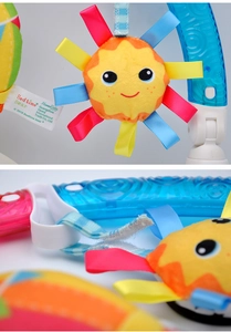 Detail view of the yellow plush sun toy with blue plastic clip for baby strollers