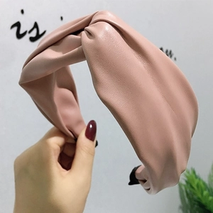 Détail d'un serre-tête en similicuir rose poudré avec un nœud croisé et texture lisse