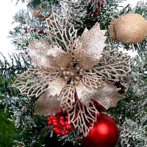 Close-up of glittery gold hollow poinsettia flower on a Christmas tree with berries