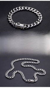 Macro view of polished 13mm silver Cuban chain bracelet on black leather texture