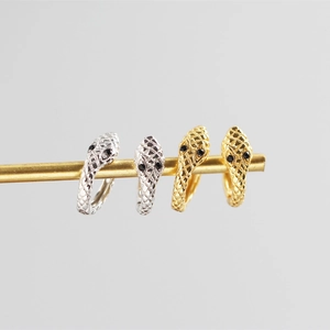 Detailed view of silver and gold snake head hoop earrings with diamond pattern textures