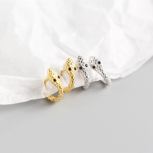 Macro shot of silver and gold snake hoop earrings with detailed scales and black gem eyes