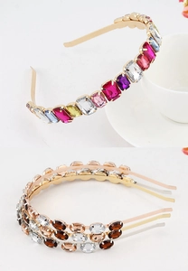 Detailed close-up of gold metal headband with inlaid colorful oversized gemstones