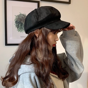 Side view of a black velvet octagonal newsboy cap worn by a model in a minimal setting