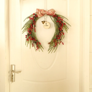 Detail of Christmas U-shaped wreath with pine needles, berries, and a vintage bow on a door