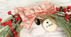 Detail of Christmas wreath with Santa bow, red berries, pine needles and X-MAS wooden tag