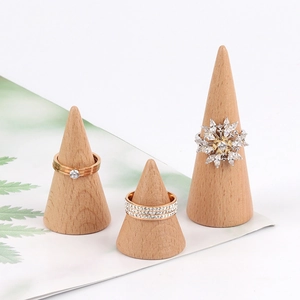 Three elegant rings displayed on minimalist solid wood cone-shaped jewelry holders