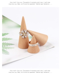 Close-up of diamond rings on cone-shaped wooden stands with a minimalist nature background