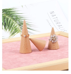 Detailed view of three solid beech wood cone ring holders on a pink velvet tray for display