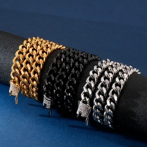 Cuban link chains in gold, black, and silver steel with diamond clasps on display stand