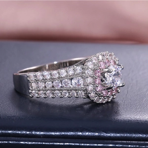 Macro shot of a luxury round cut ring with pink side stones on blue leather background