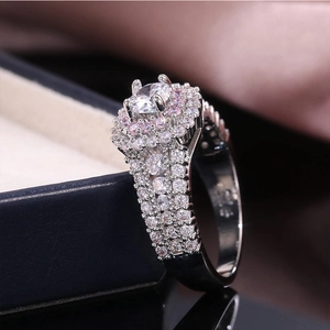 Detail of S925 silver princess ring with pink halo stones on a blue jewelry box