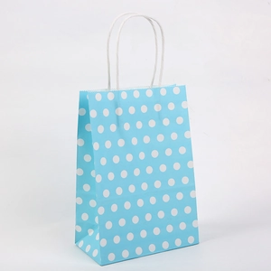 Détail d'un sac cadeau en papier kraft bleu à pois blancs avec poignées en corde