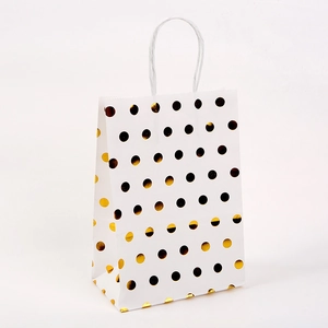 Detail of white paper gift bag with golden foil polka dots and durable white handles
