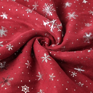 Détail d'une écharpe de Noël rouge avec motifs flocons argentés et texture coton doux