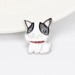 Close-up of black and white enamel dog brooch with a red collar on a white plate