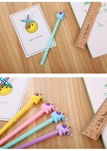 Detail of cute elephant silicone toppers on colorful neutral pens on a wooden desk