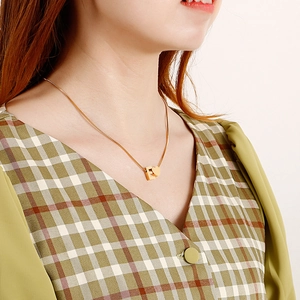 Minimalist stainless steel pull-tab necklace with heart and letter E pendant on a female model