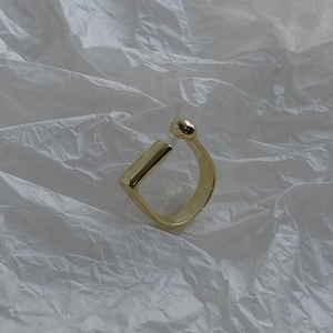 Detail of a minimalist gold-plated 925 silver D-shape ring with sphere and bar ends