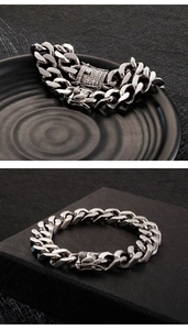 Detail of silver Cuban link bracelet with iced-out rhinestone box clasp on black surface