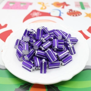 Close-up of purple resin gift box charms with silver ribbons in a white dish