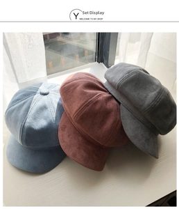 Detail of three faux suede newsboy caps in light blue, dark grey, and brown colors