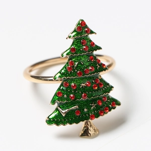Detail of golden napkin ring featuring green enamel Christmas tree and red rhinestones