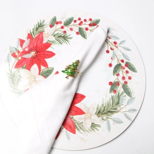 Detail of Christmas tree napkin ring with green enamel and red pearls on a white napkin