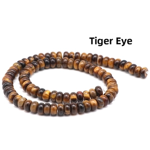 Macro shot of polished brown Tiger's Eye rondelle beads in a spiral layout on white base