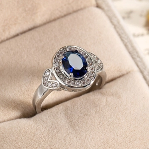 Macro shot of silver ring with oval royal blue gemstone on beige velvet box